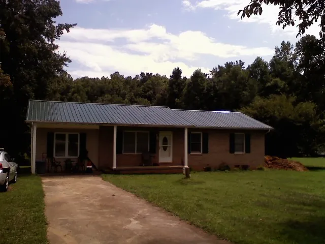 Dark green metal roof on a brick ranch with a covered porch in Venus