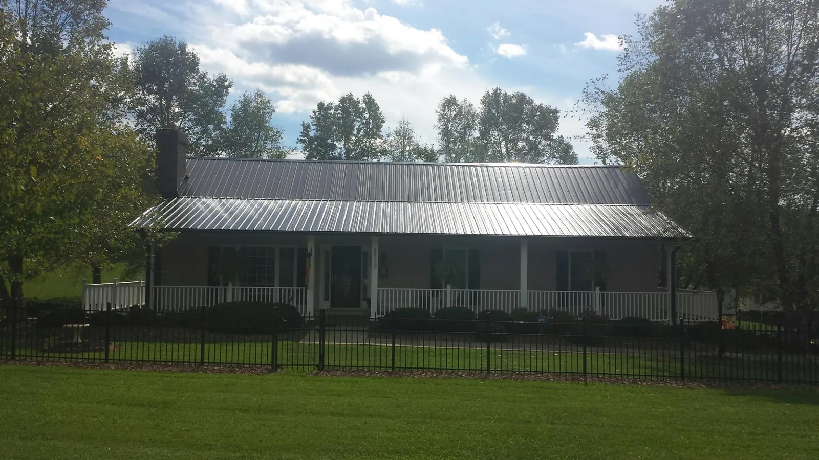 Gray metal roof on a brick ranch with a full width front porch — Gutter Guard Installation work by our crew in Venus