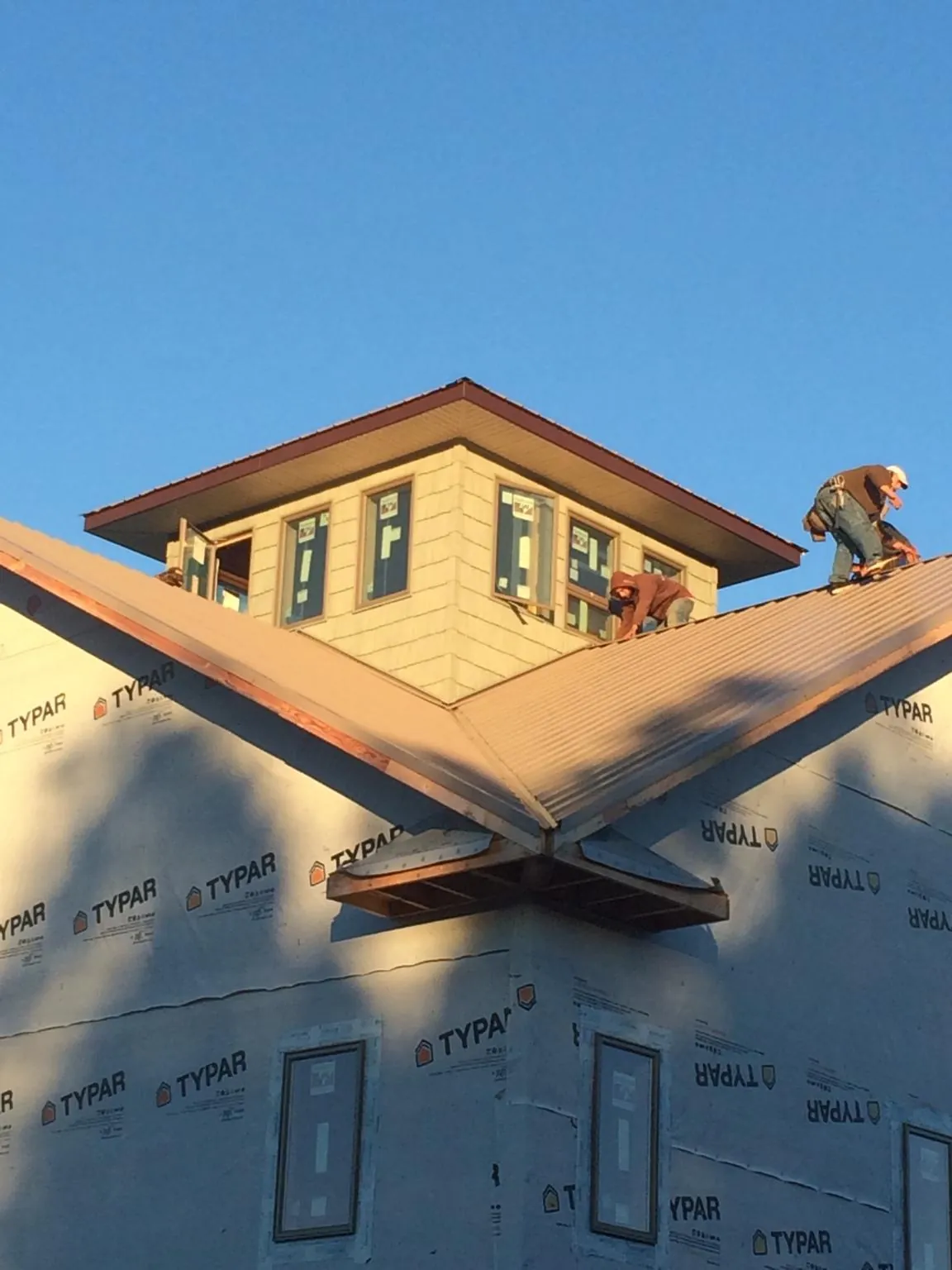 Roofers working around a rooftop cupola on a new metal roof at sunset — Roof Waterproofing in Venus by Roofing Brothers